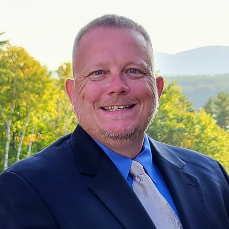 a man wearing glasses and smiling at the camera