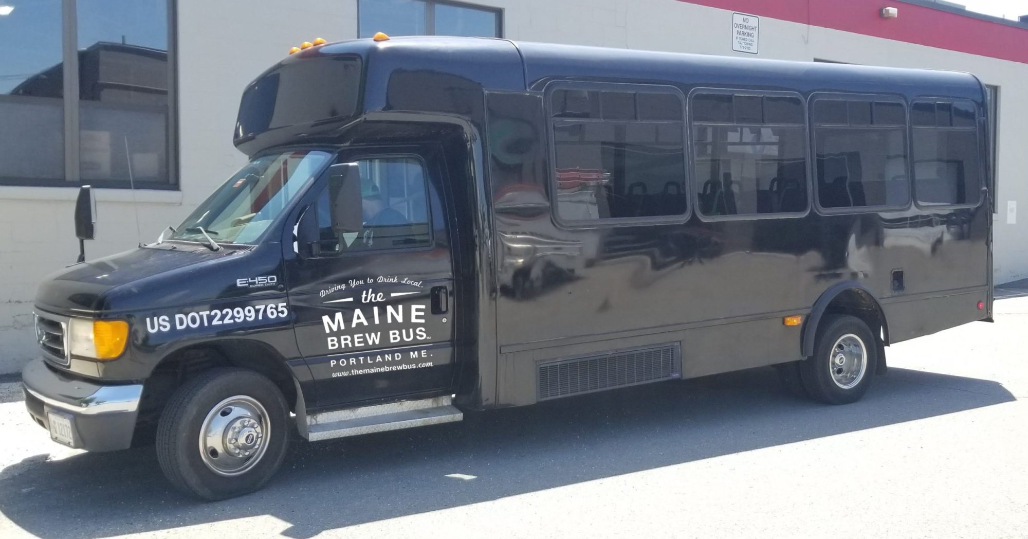 Black shuttle bus with 'The Maine Brew Bus' logo parked on street.