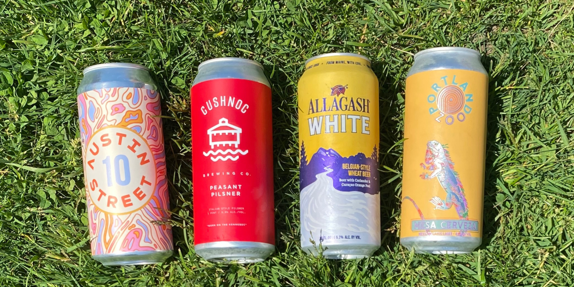 Four colorful beer cans lying on the grass.