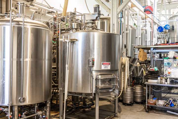 Industrial brewery with large stainless steel tanks and equipment.