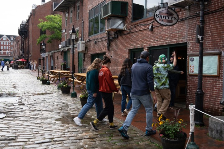 Group entering a rustic brick pub named Gritty's on a cobblestone street.