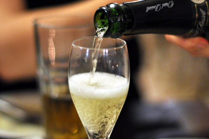 Sparkling wine being poured into a flute glass, with a blurred background.