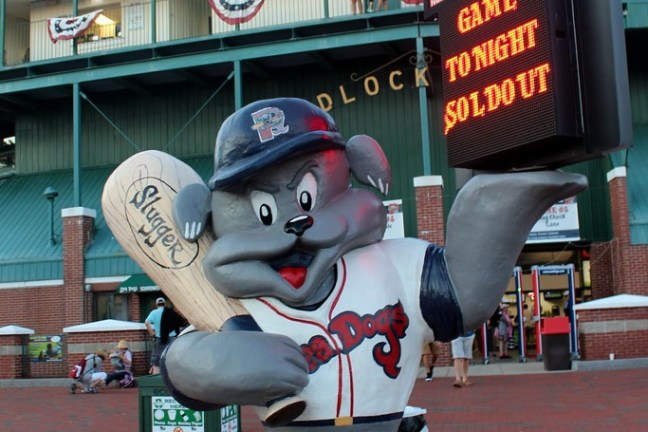 Statue of a dog mascot holding a bat, in front of a stadium with a sold-out sign.