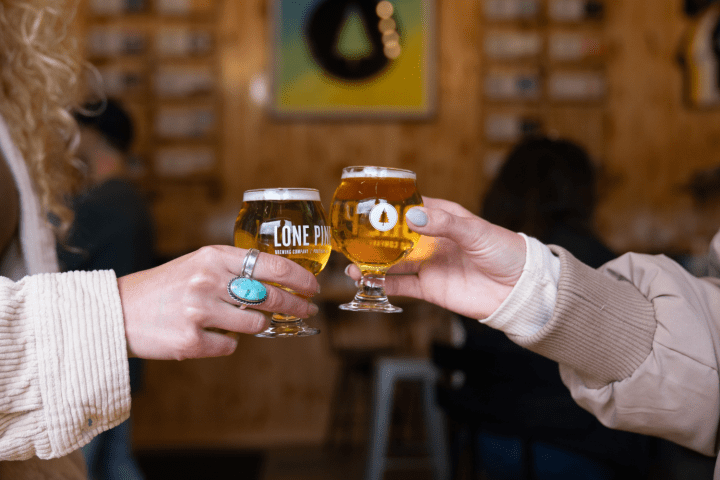 Two people toasting with beer glasses in a cozy pub setting.
