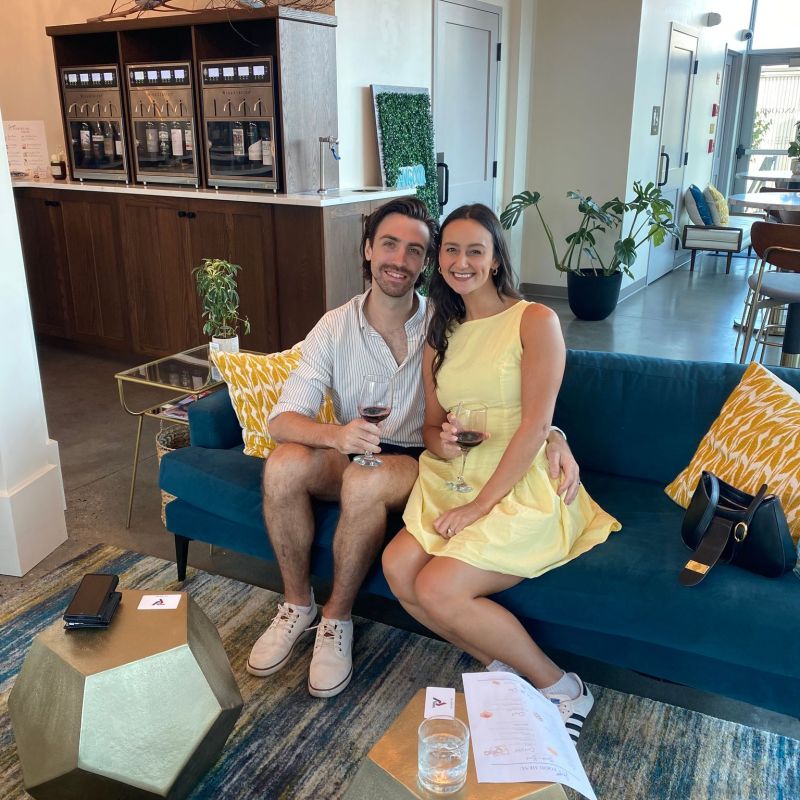 Couple seated on a blue sofa in a modern room, holding wine glasses.