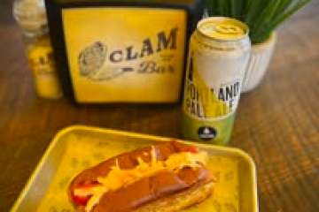Lobster roll on a tray with a canned drink and plant on a table.