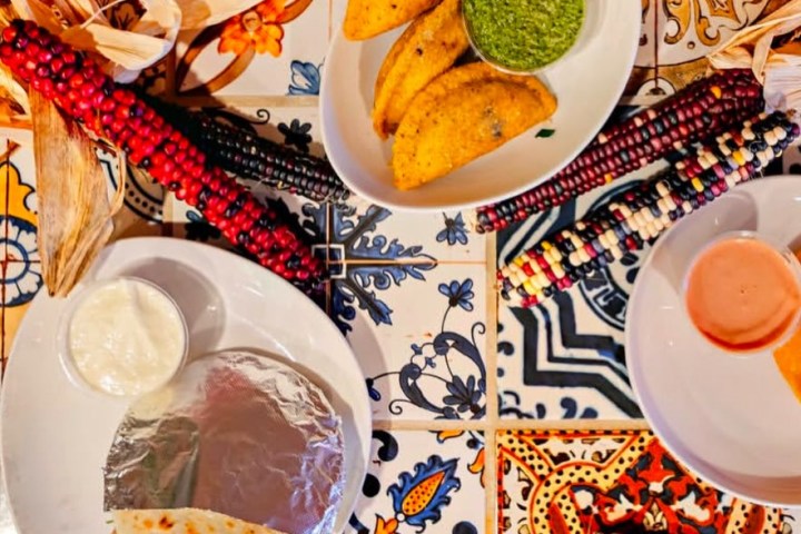Colorful tiles with tacos, sauces, and decorative corn.